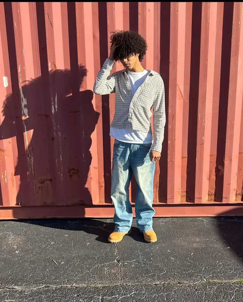 A young man stands in front of a red shipping container, part of the mindfulness photography program
