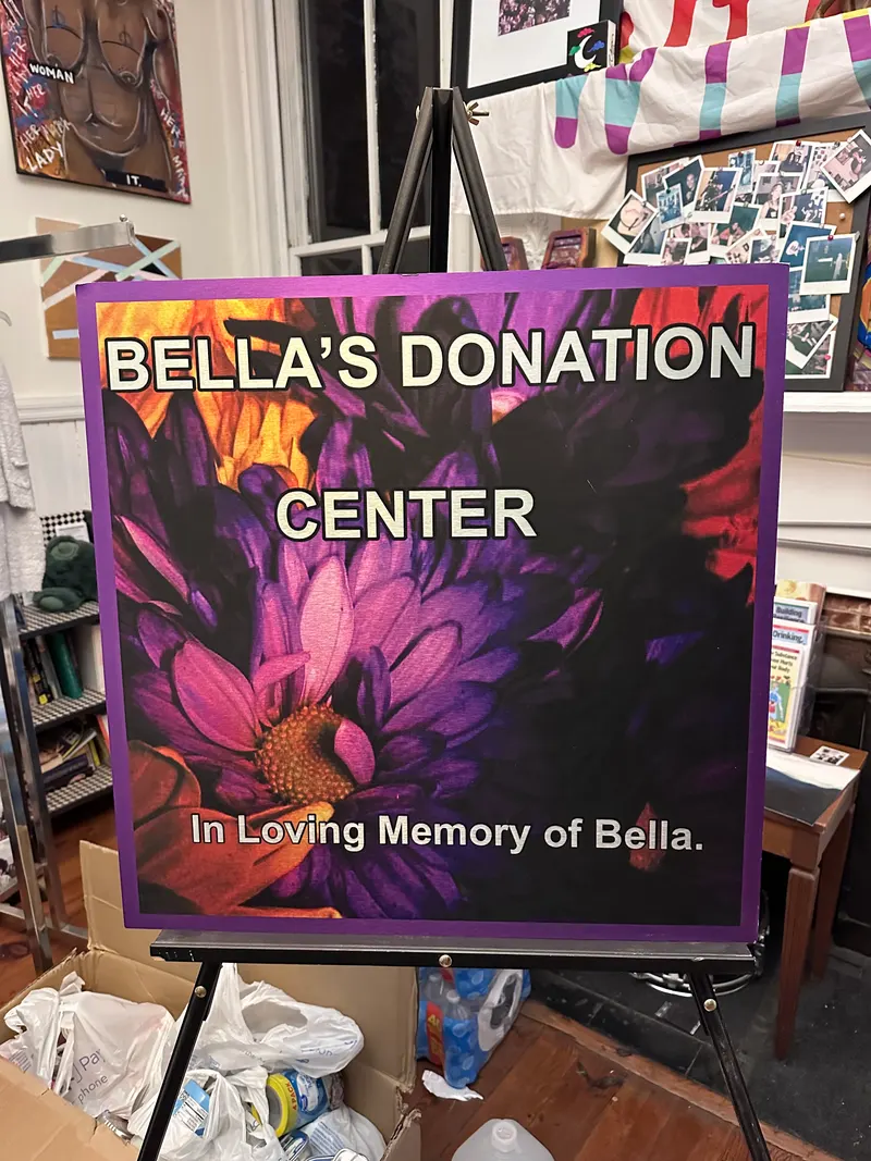 A hand-painted sign for Bella's Free Community Store on an easel