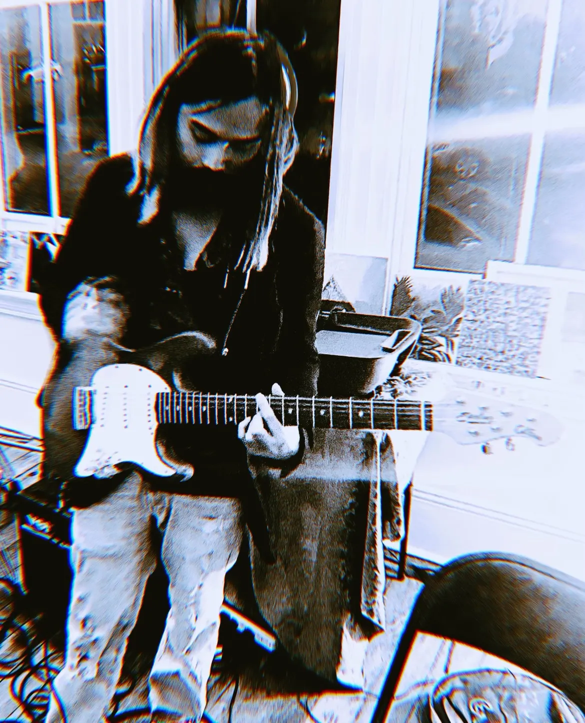 A person sits by a bright window at The Clarity House playing guitar