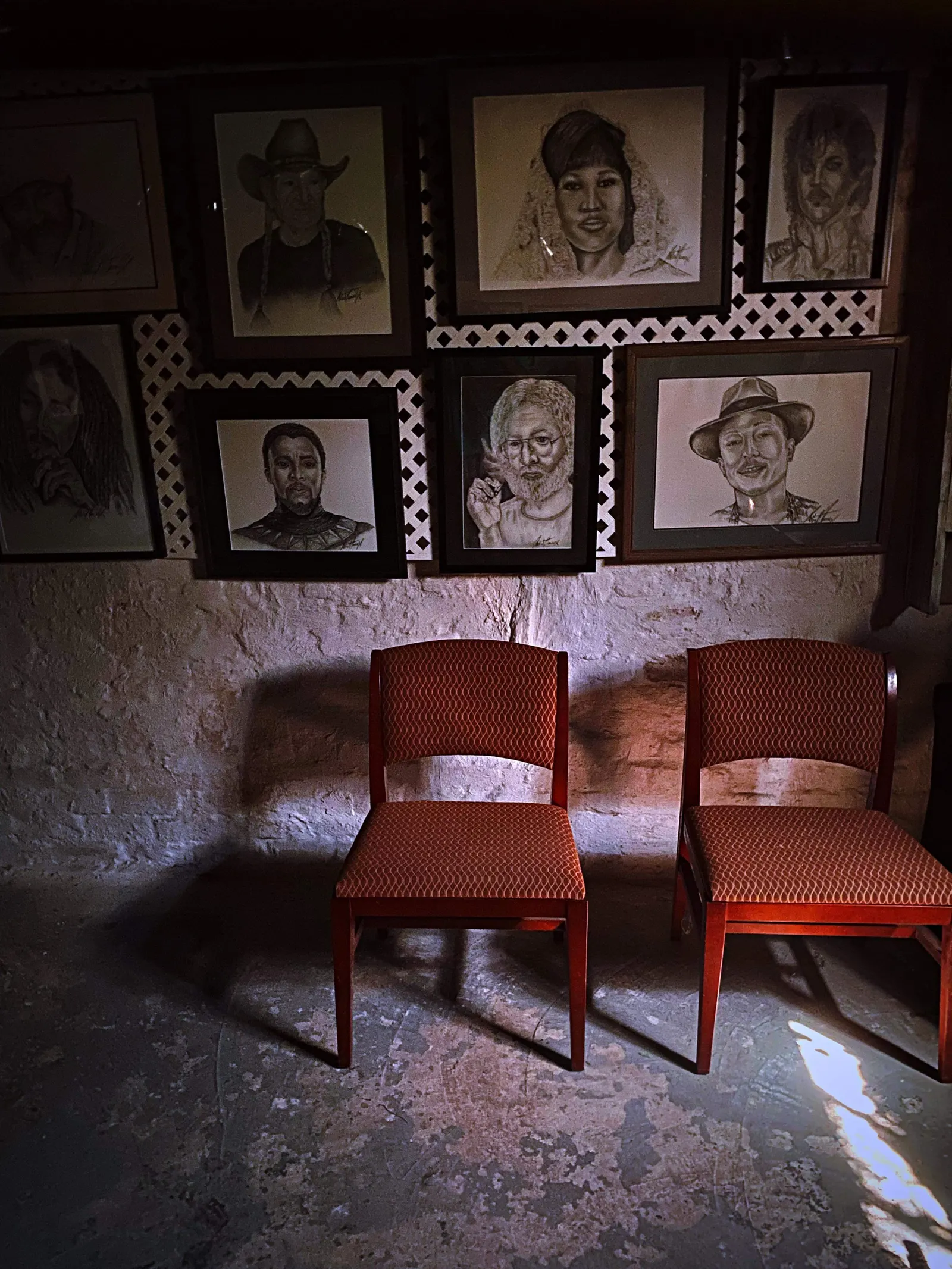 Two red chairs beneath a wall of hand-drawn portraits inside The Clarity House